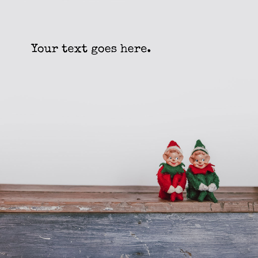 Two Christmas elf figurines on a wooden surface