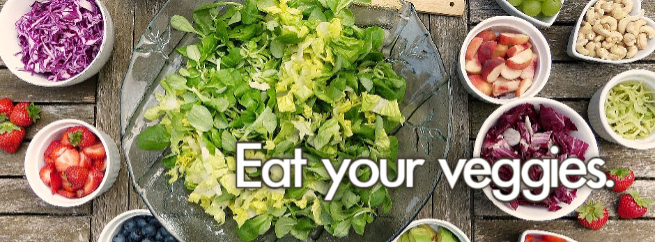 A colorful salad bowl surrounded by various toppings and ingredients