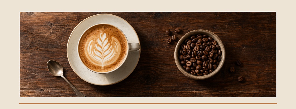 Top-down coffee cup with latte art, spoon, and bowl of coffee beans on a wooden table