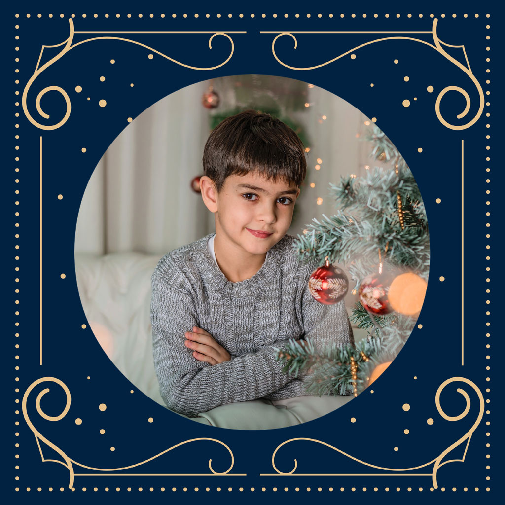 Young boy sitting by a Christmas tree