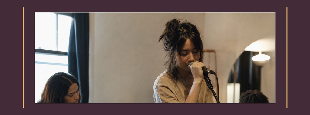 Female singer performing into a microphone on a dimly lit jazz stage.