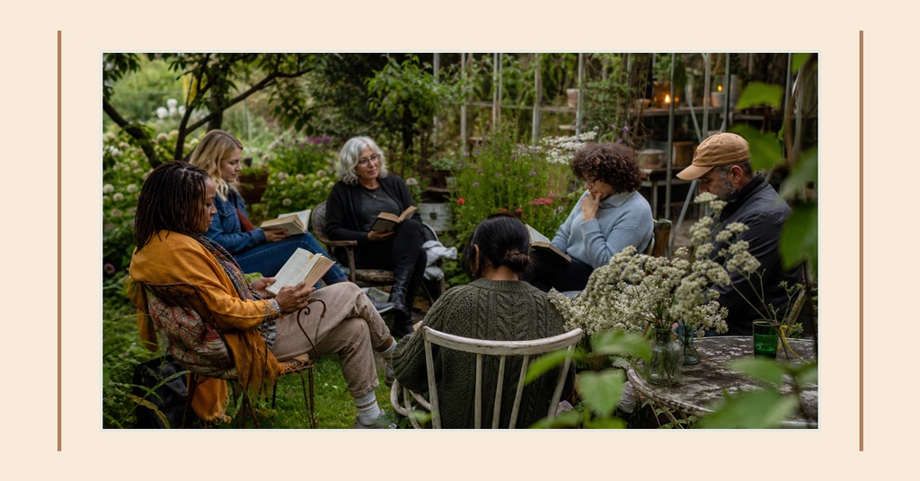 People sitting outdoors in a garden and reading books together.