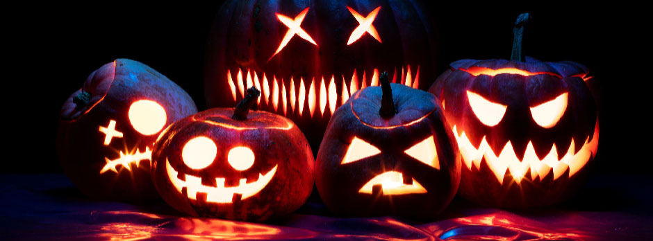 A group of five carved pumpkins with different designs lit up at night