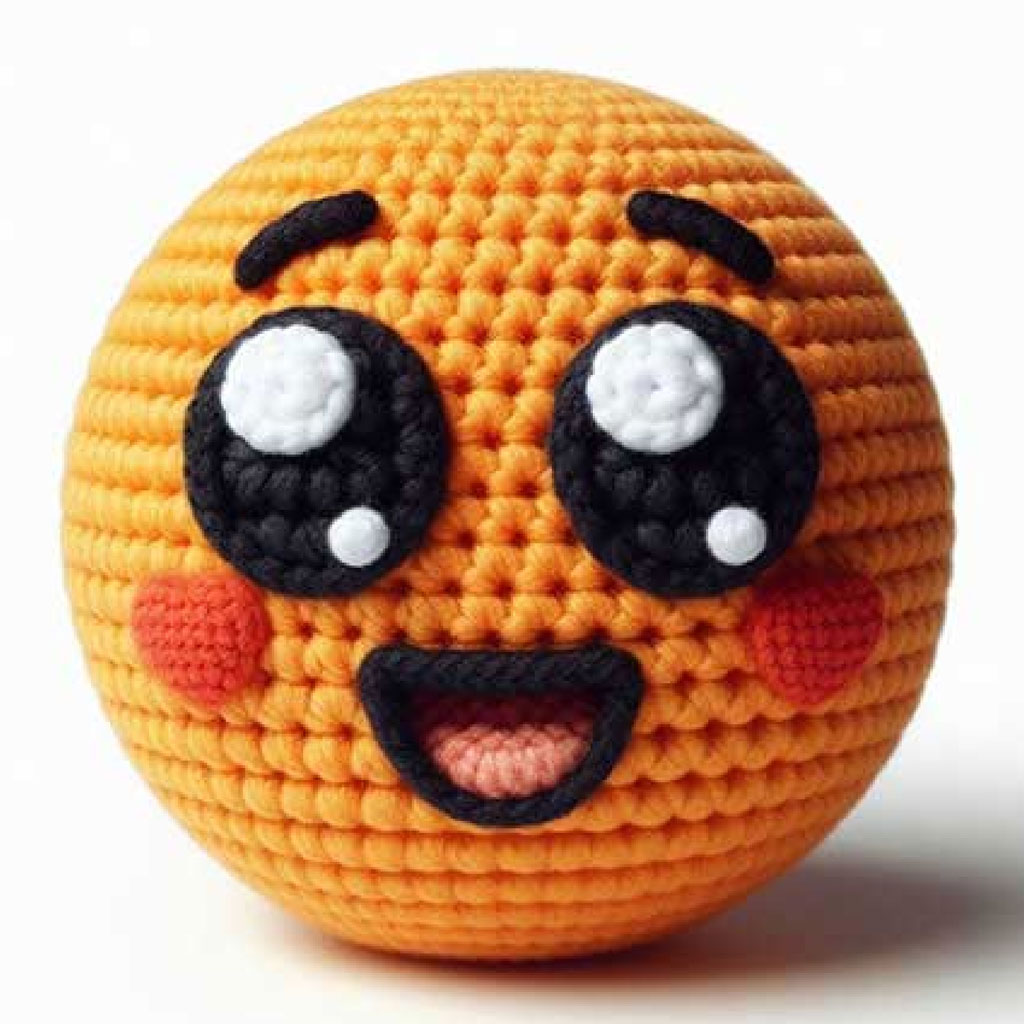 A crocheted orange emoji toy with a smiling face