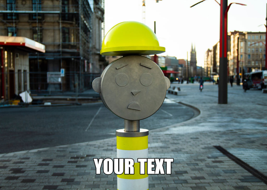 Metal face sculpture with yellow hard hat on a pole