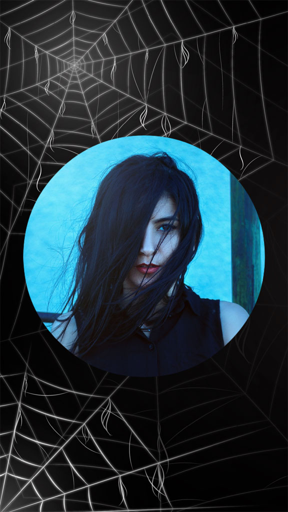 A woman with long dark hair and red lips is visible through a circular cutout in a black background covered with a spider web.