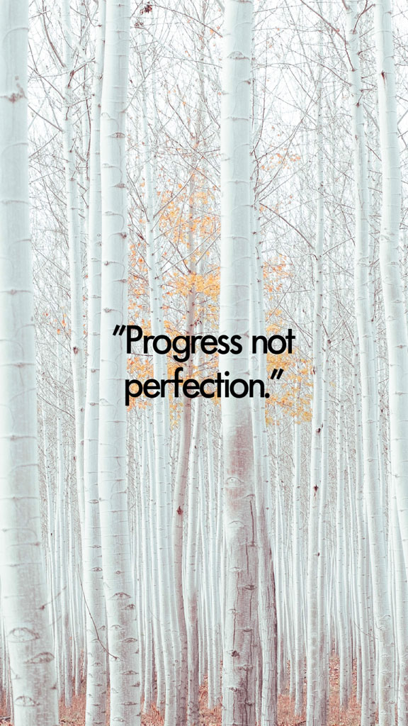A serene forest with white trees and a motivational quote 'Progress not perfection.'