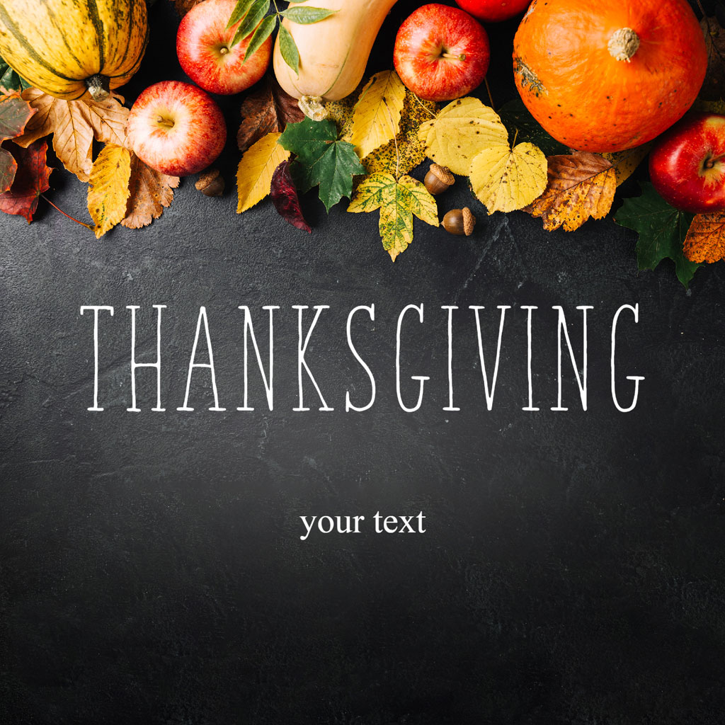 Assorted pumpkins and apples with leaves on a dark surface