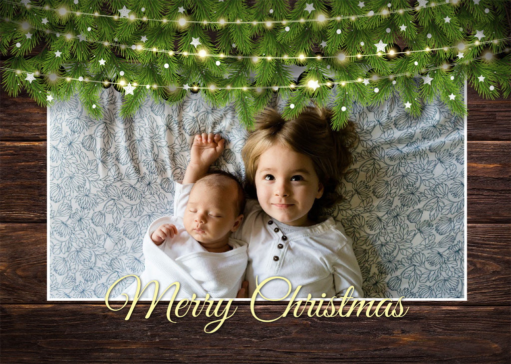 Two children in white lying under a Christmas garland with lights