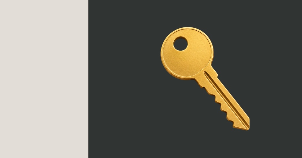 Gold key on a split beige and dark gray background.