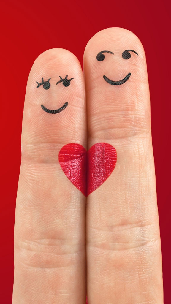 Two fingers with painted smiley faces and a heart between them