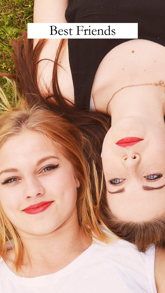 Two young women lying on the grass, heads tilted towards the camera