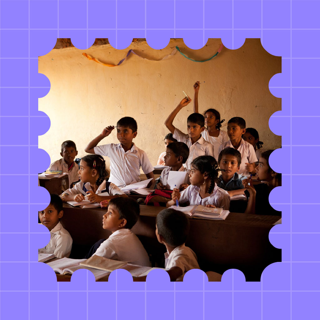 Students in white shirts sitting at desks, raising hands and participating in class