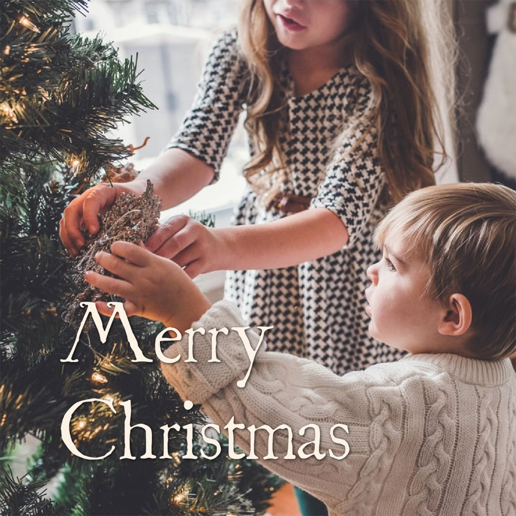 Two children decorating a Christmas tree together