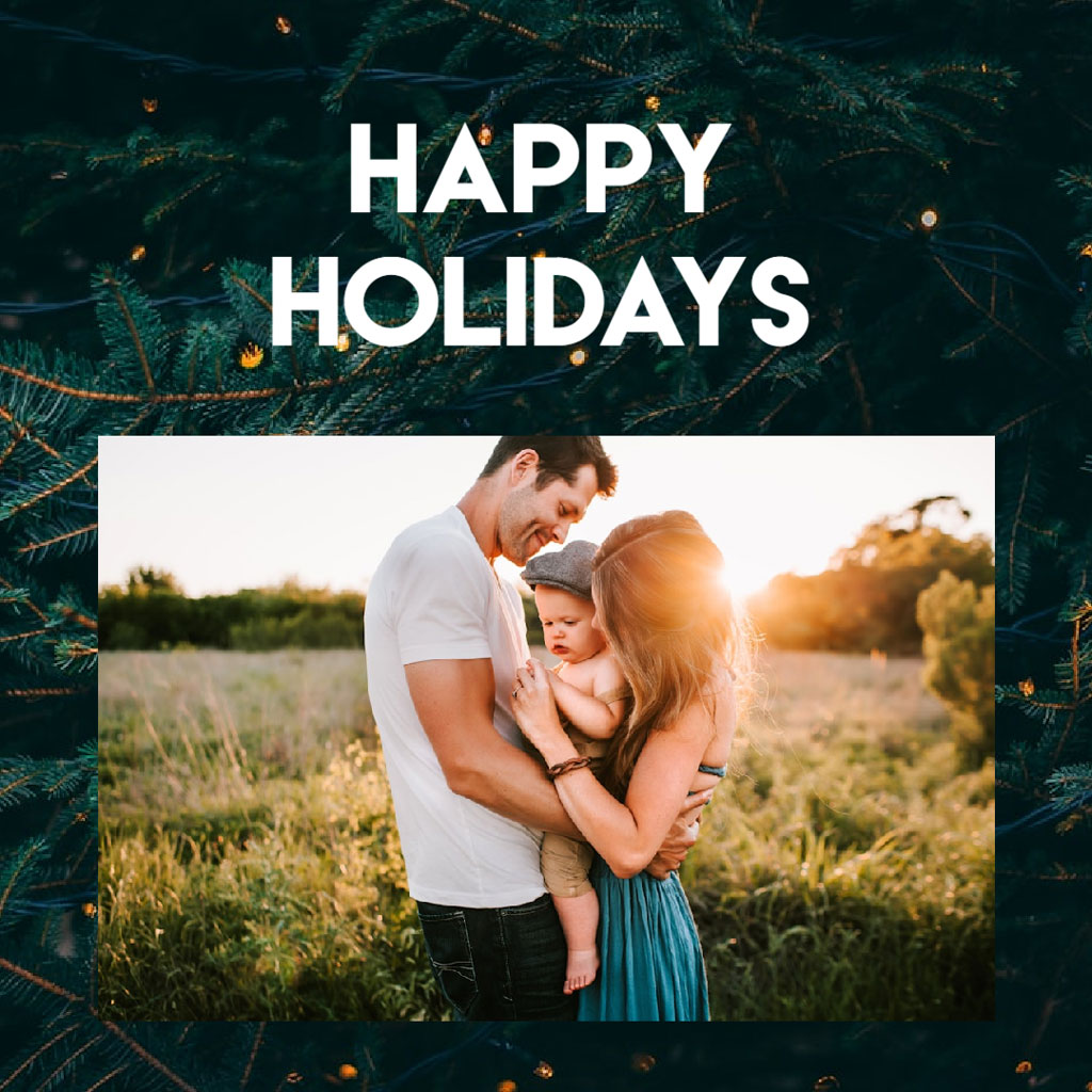 A man, woman, and baby embracing in a field with a festive holiday message.