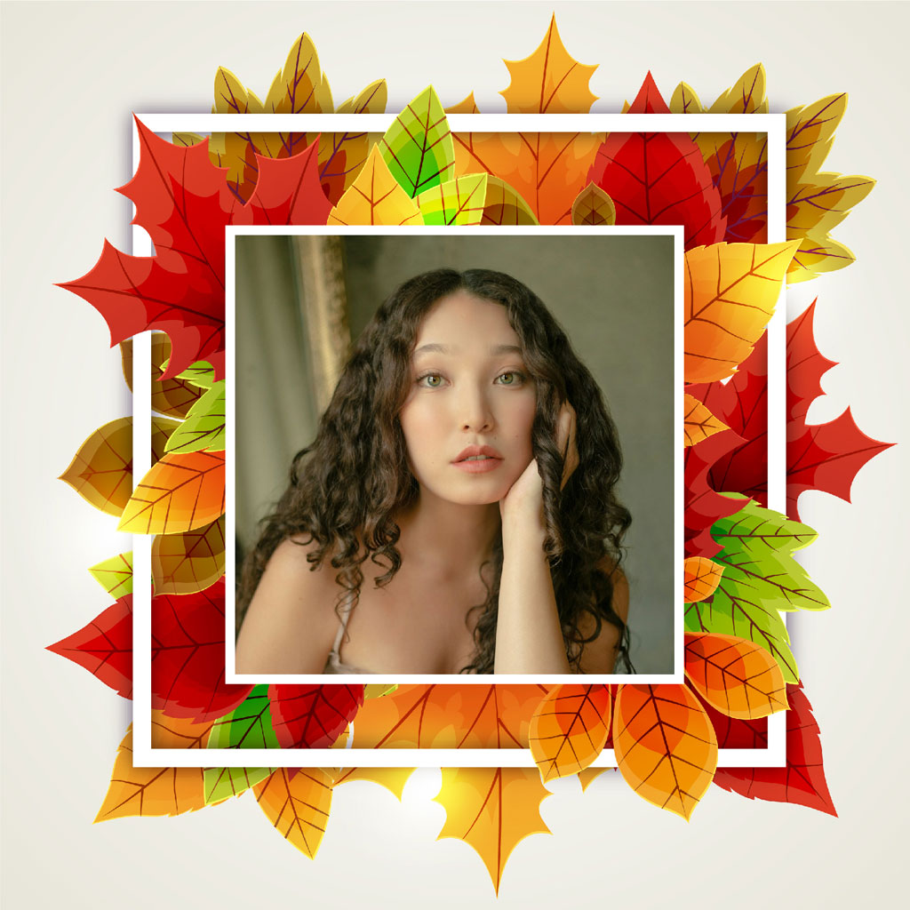 Woman with curly hair surrounded by autumn leaves