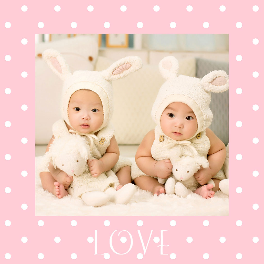 Two babies in bunny hats and outfits holding stuffed animals