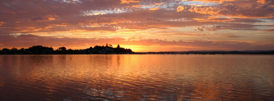 A serene lake with a vibrant sunset in the background