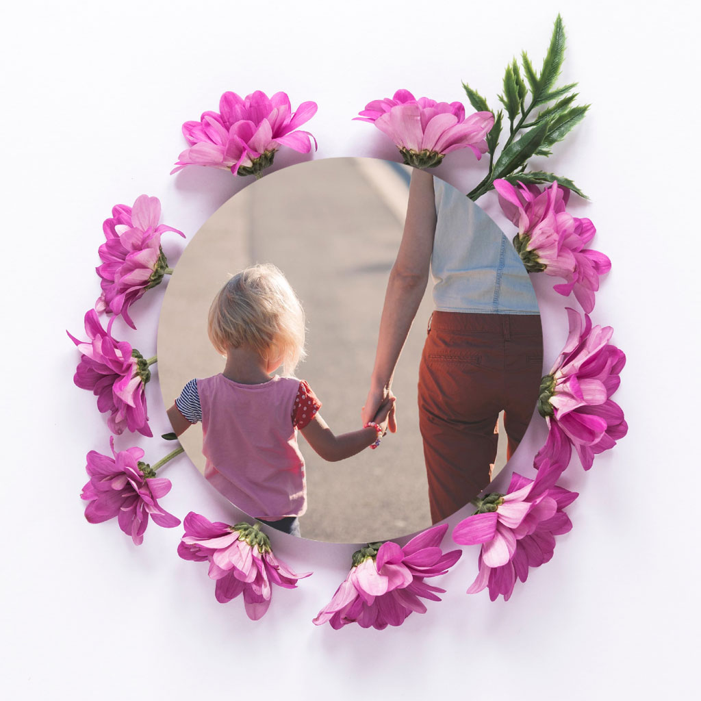 A mother and child holding hands, viewed through a circular frame adorned with pink flowers.