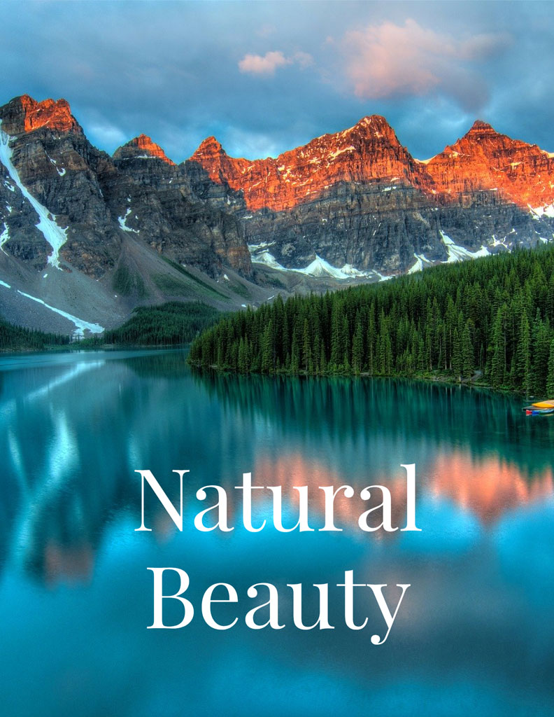 Mountain range with snow and trees reflected in a calm lake.