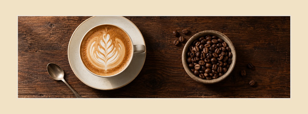 Coffee cup with latte art, spoon, and bowl of coffee beans on a wooden surface