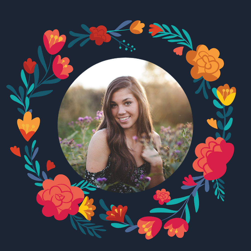 A smiling woman with long brown hair in a field of flowers, surrounded by a colorful floral wreath.