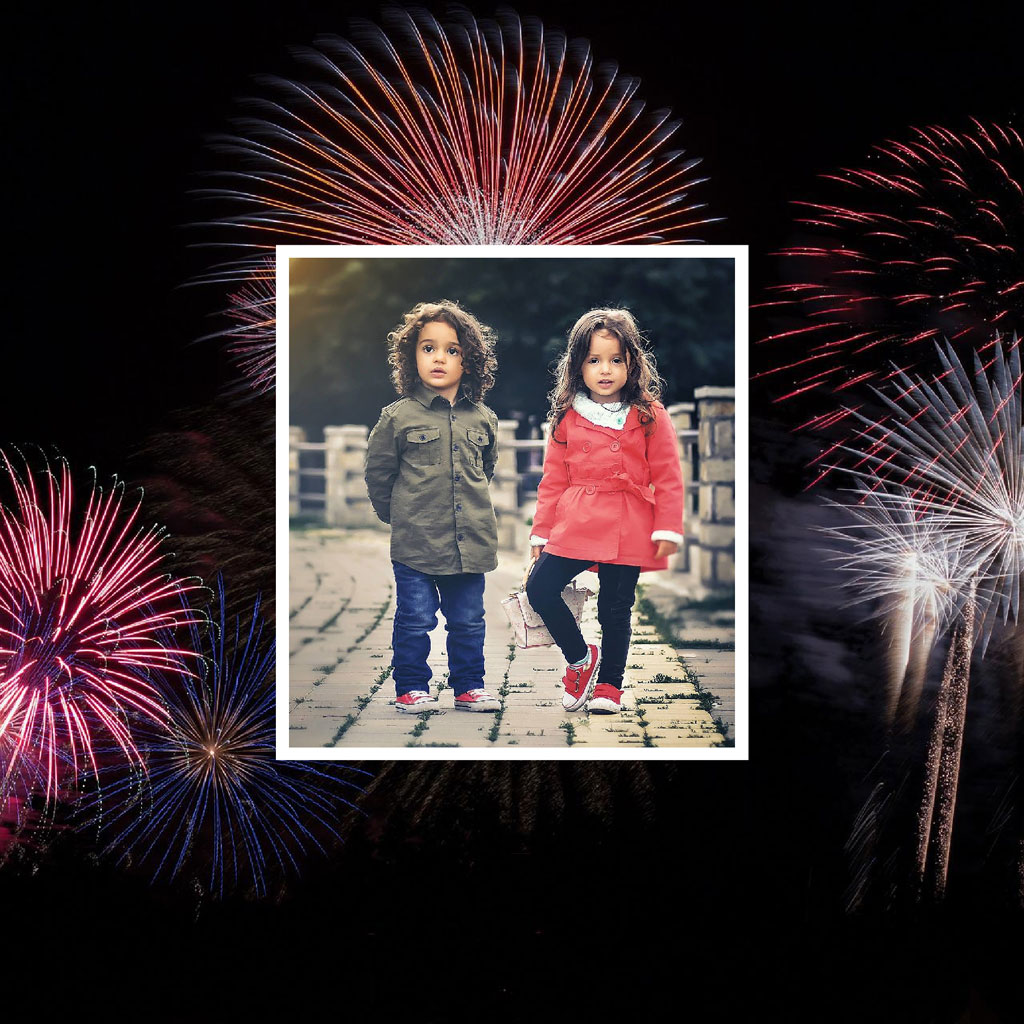 Two children walking on a pier with fireworks exploding around them